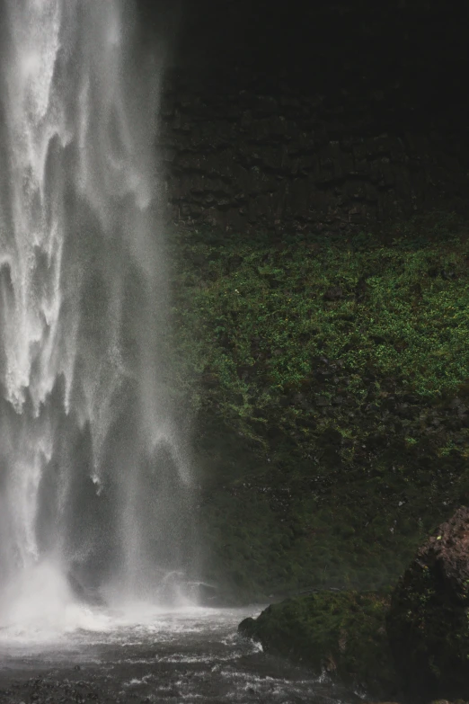 a waterfall with water coming from it and people walking near