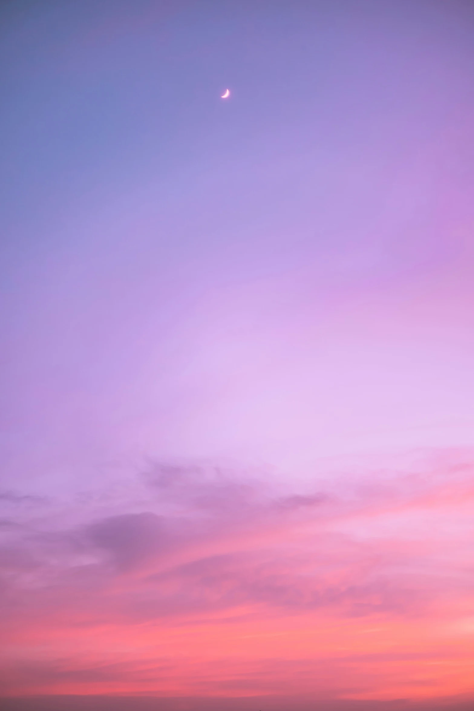 a distant bright pink sunset is captured from the shore line