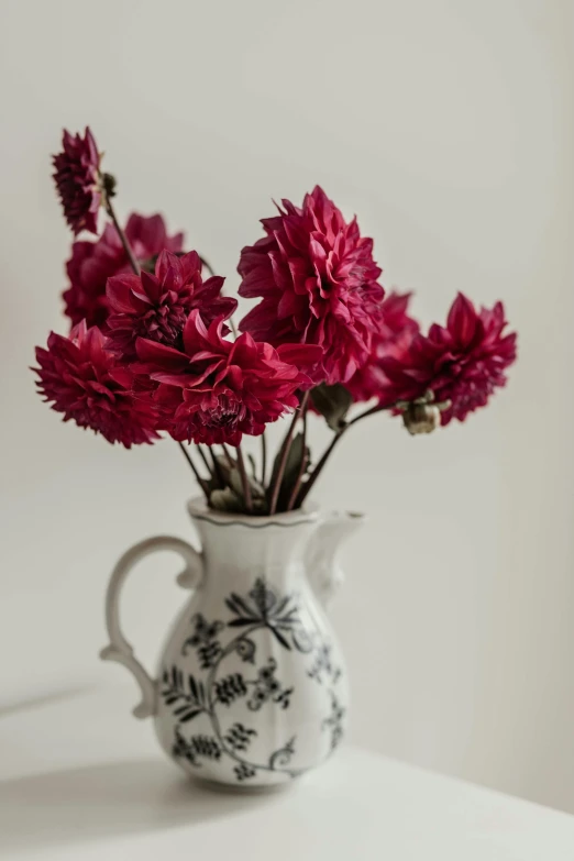 a white and black vase filled with red flowers