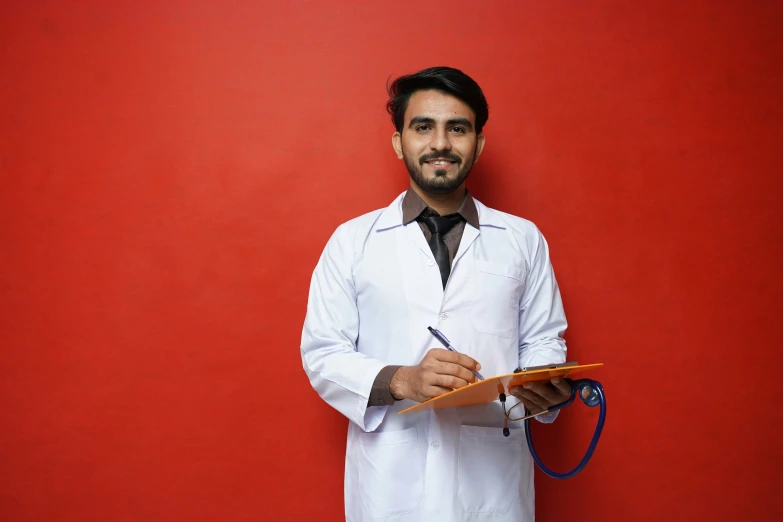 a man holding a clipboard while standing next to a red wall