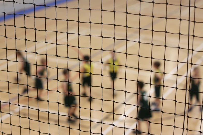 a blurry s of some people in green vests and sports uniforms playing volleyball