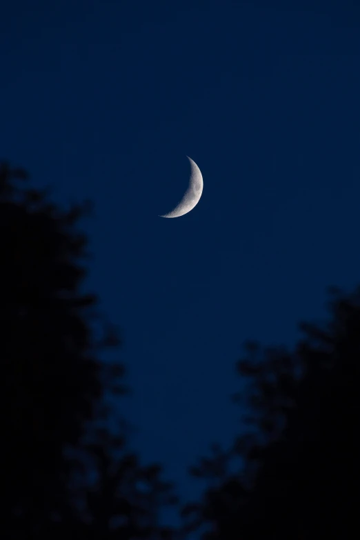 a crescent moon that is against a blue sky