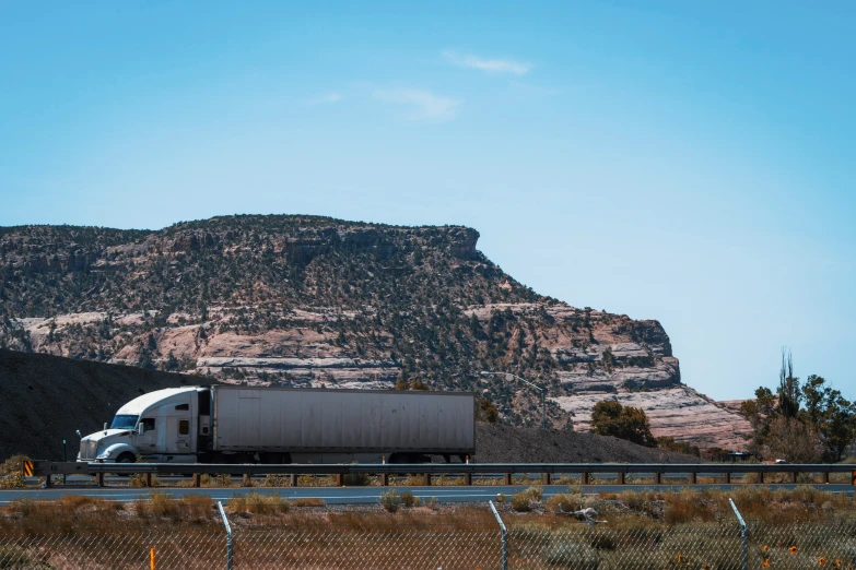 a semi truck is going down the highway in front of a mountain