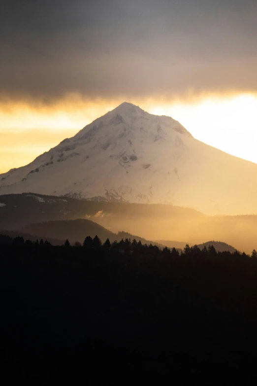 sun peeking through the clouds as it peeks over a mountain