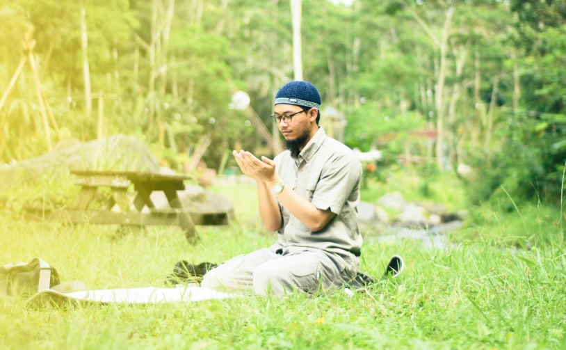 a man kneeling down in the grass praying