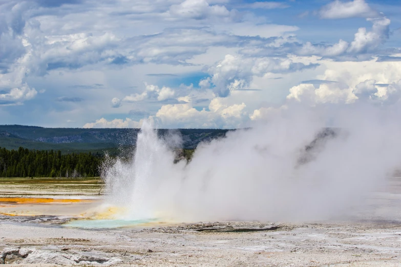 a large geyser spewing water in a barren area