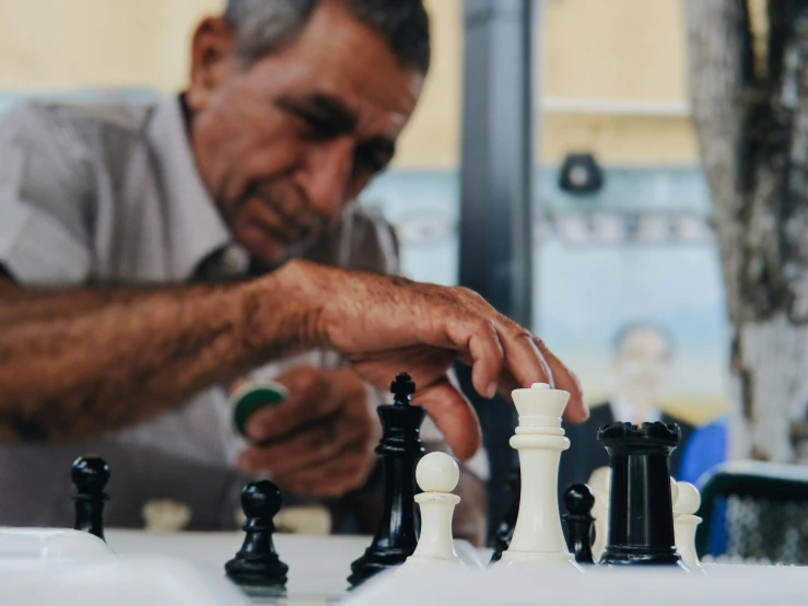 an older man playing chess with the pieces missing