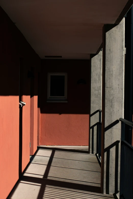 shadows come from an orange wall next to an empty staircase