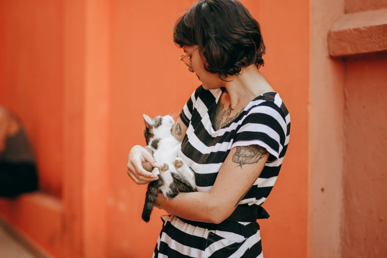 the woman in striped shirt holds a cat outside