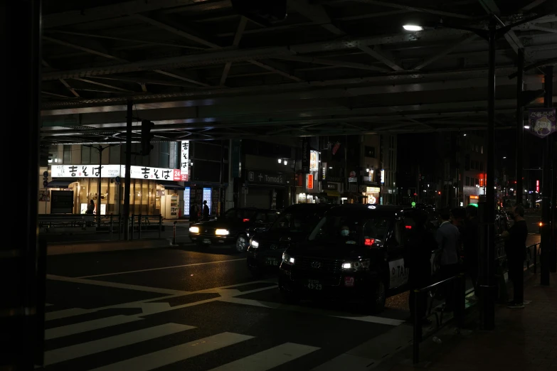 cars stopped at a curb while people wait for their bus