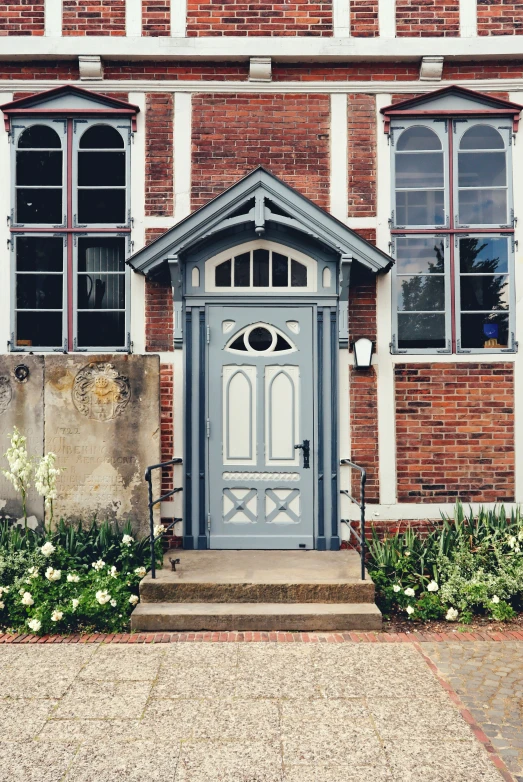 an entry to a large brick building with flowers and greenery