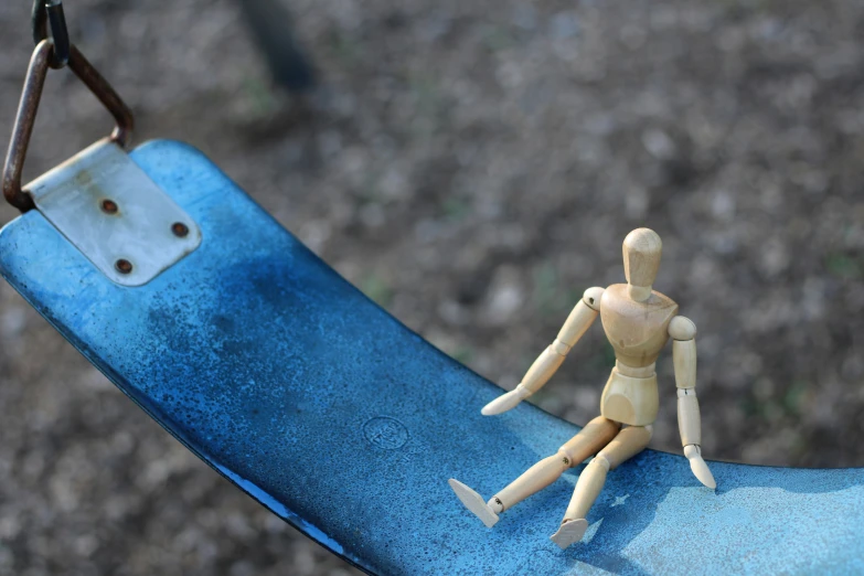 the little toy man is sitting on a blue swing