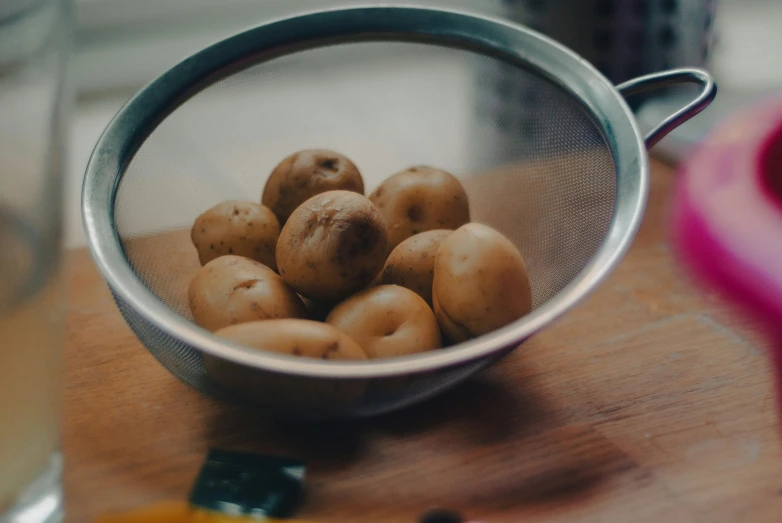 a metal strainer filled with some little potatoes