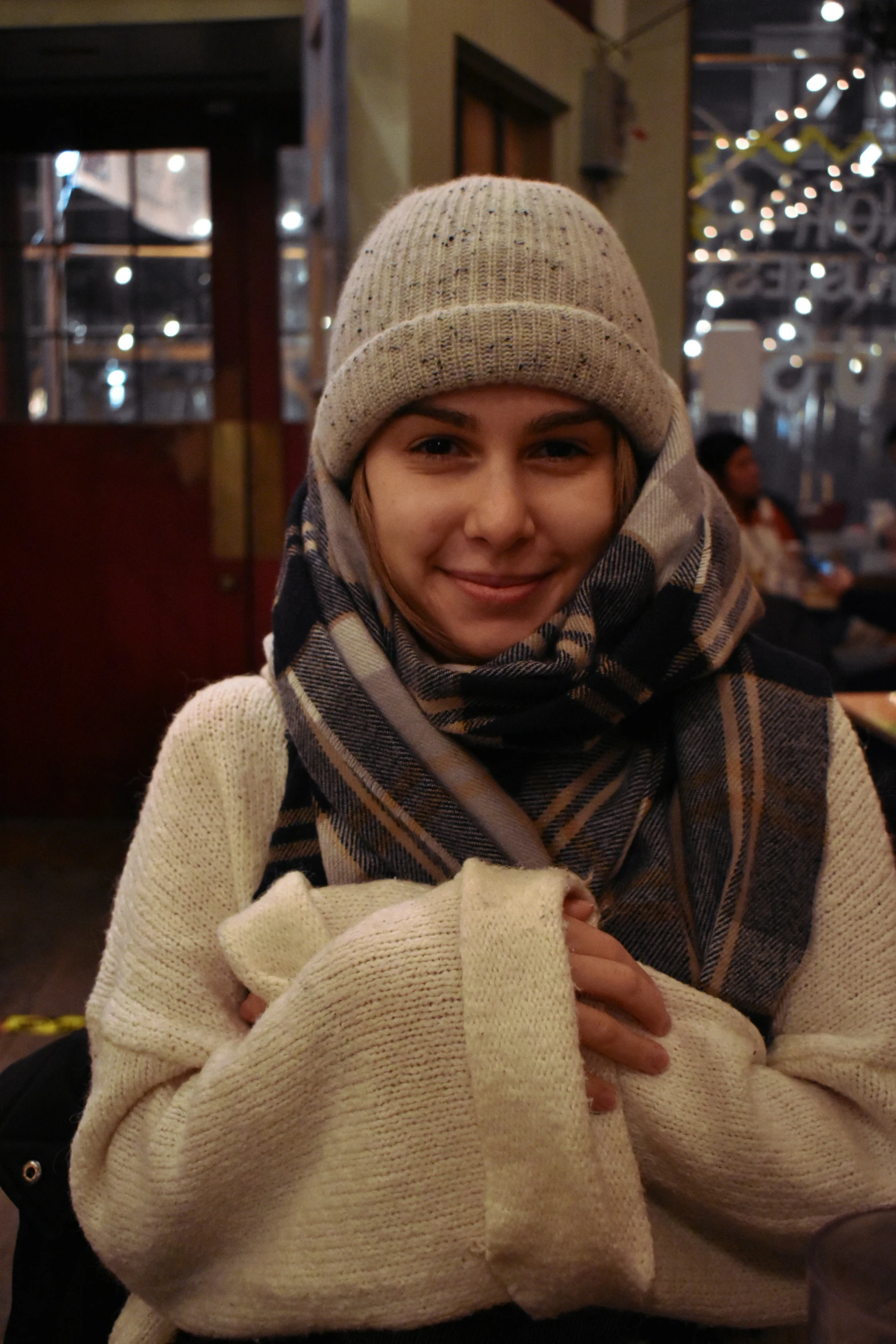 a smiling girl wearing a scarf and a hat