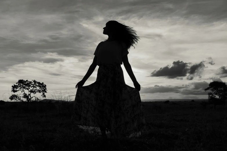 a woman standing in a field next to a tree