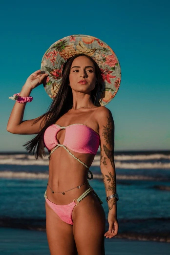 a woman with tattoos, pink bikini and hat on