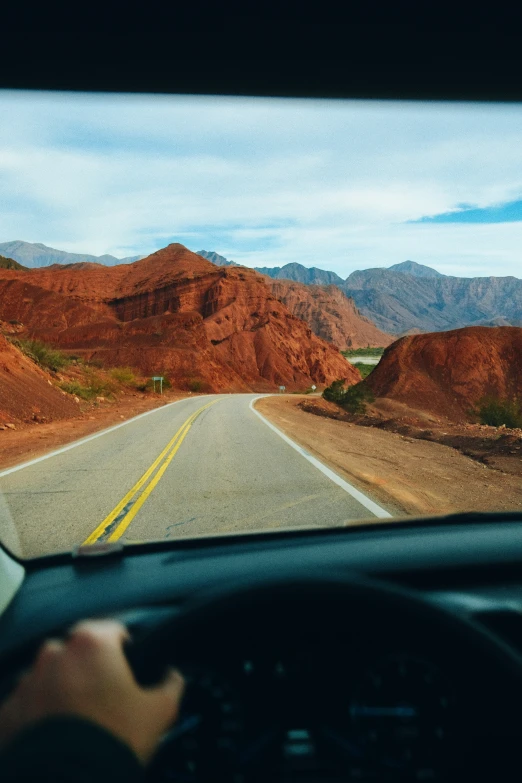 a car driving down the highway while on its way to red mountains