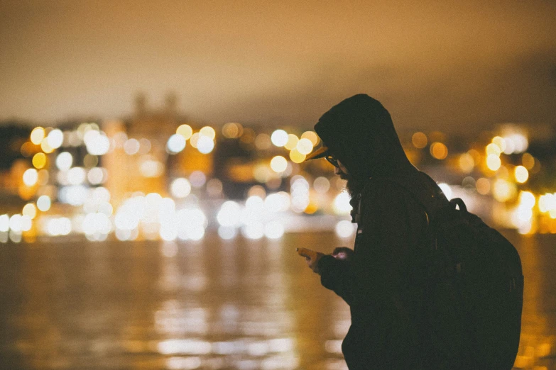 a man using a phone while standing near water