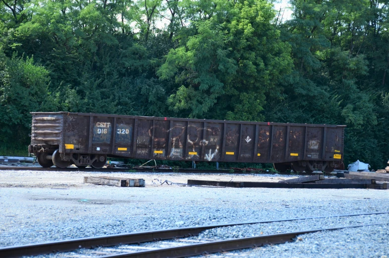 a train car on the train tracks next to a wooded area