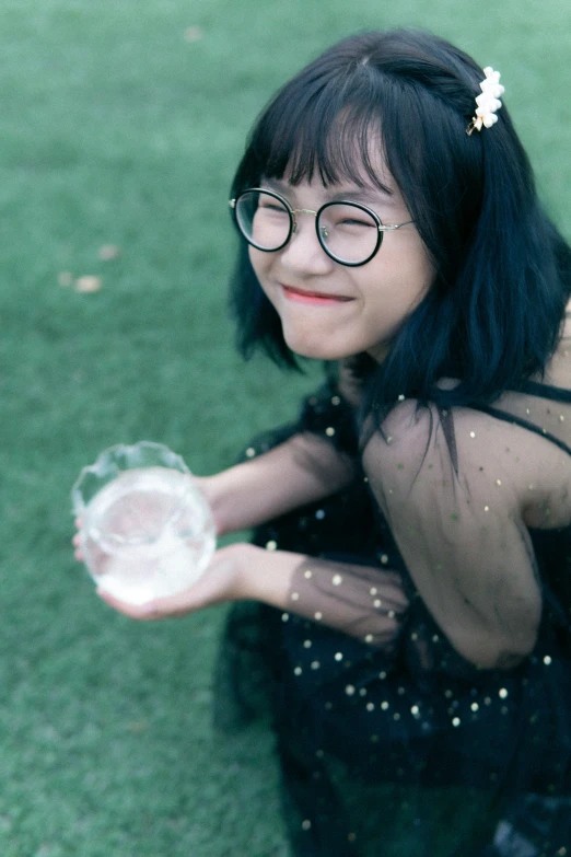 a woman in a black dress and glasses holding up a frisbee