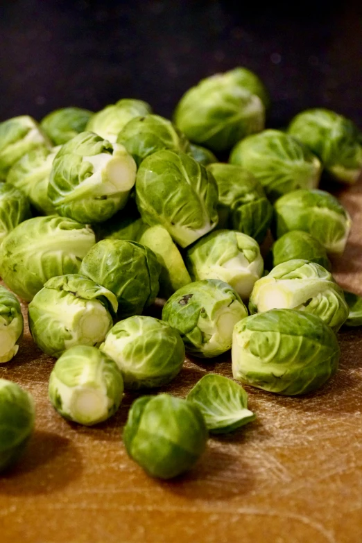 a wooden  board topped with lots of fresh brussel sprouts