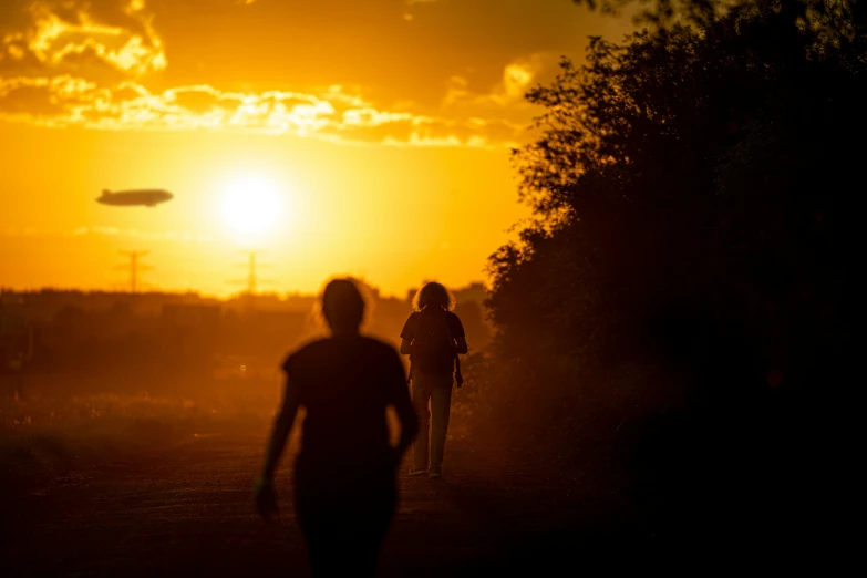 the sun sets in the background while three people are walking