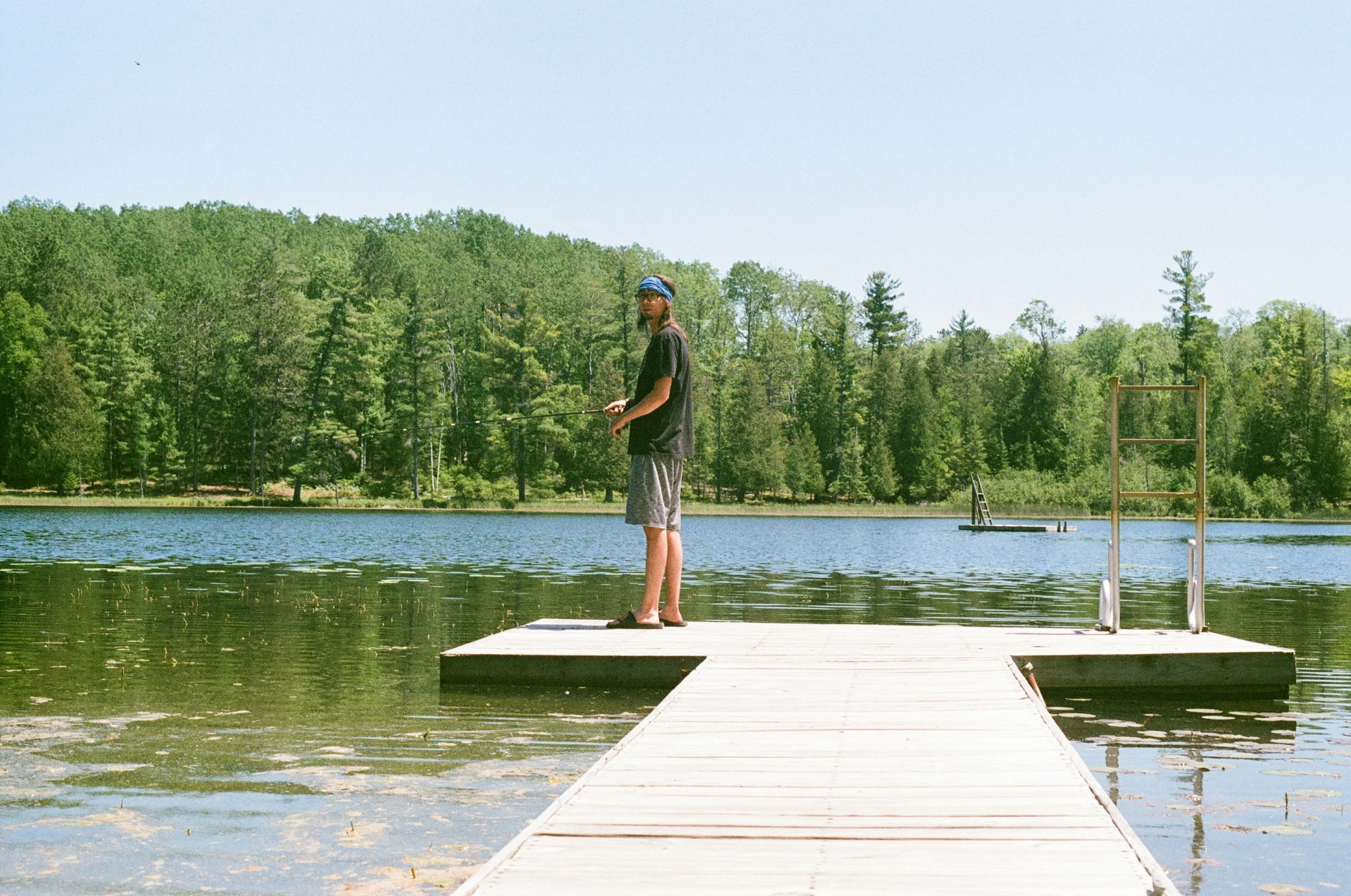 a man standing at the end of a pier on top of a lake