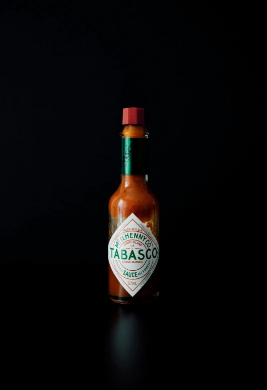 a small bottle of tabasco sauce on a black table