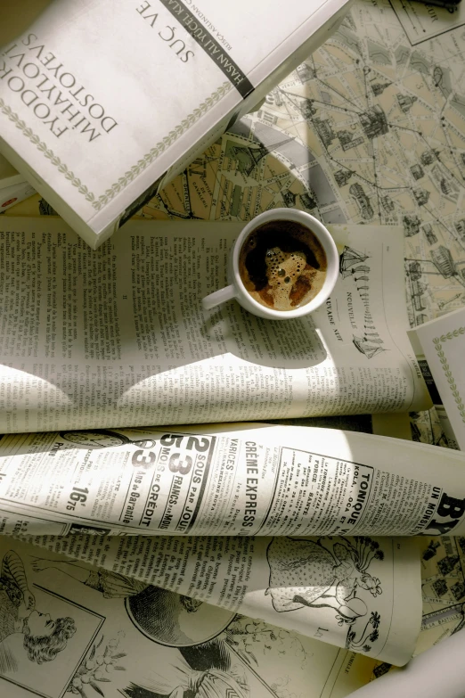 newspaper, coffee mug, and book sit on a table