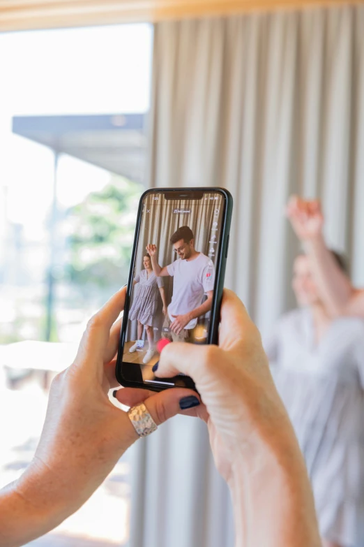 woman taking po of her family in mirror while man on cell phone