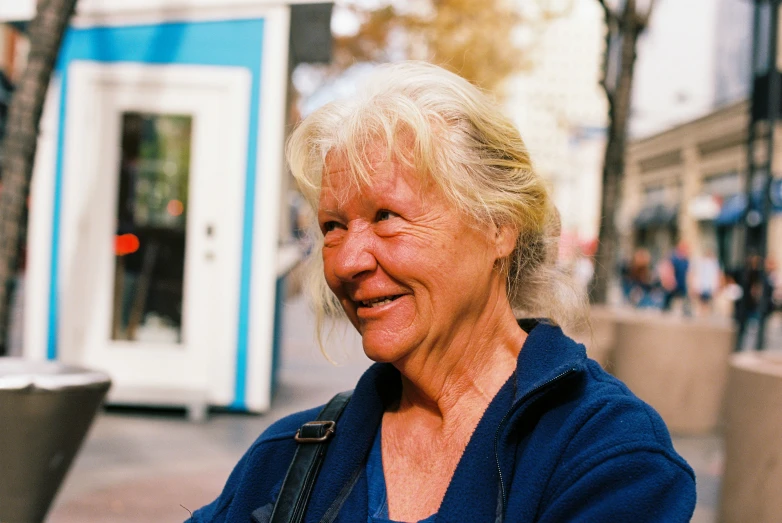 an older woman standing in front of a blue and white building