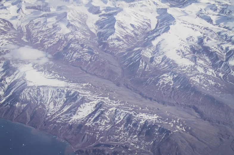 a snow - covered mountain range, from an airplane window