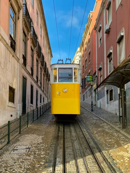 a yellow trolly passes through old buildings and cobblestones