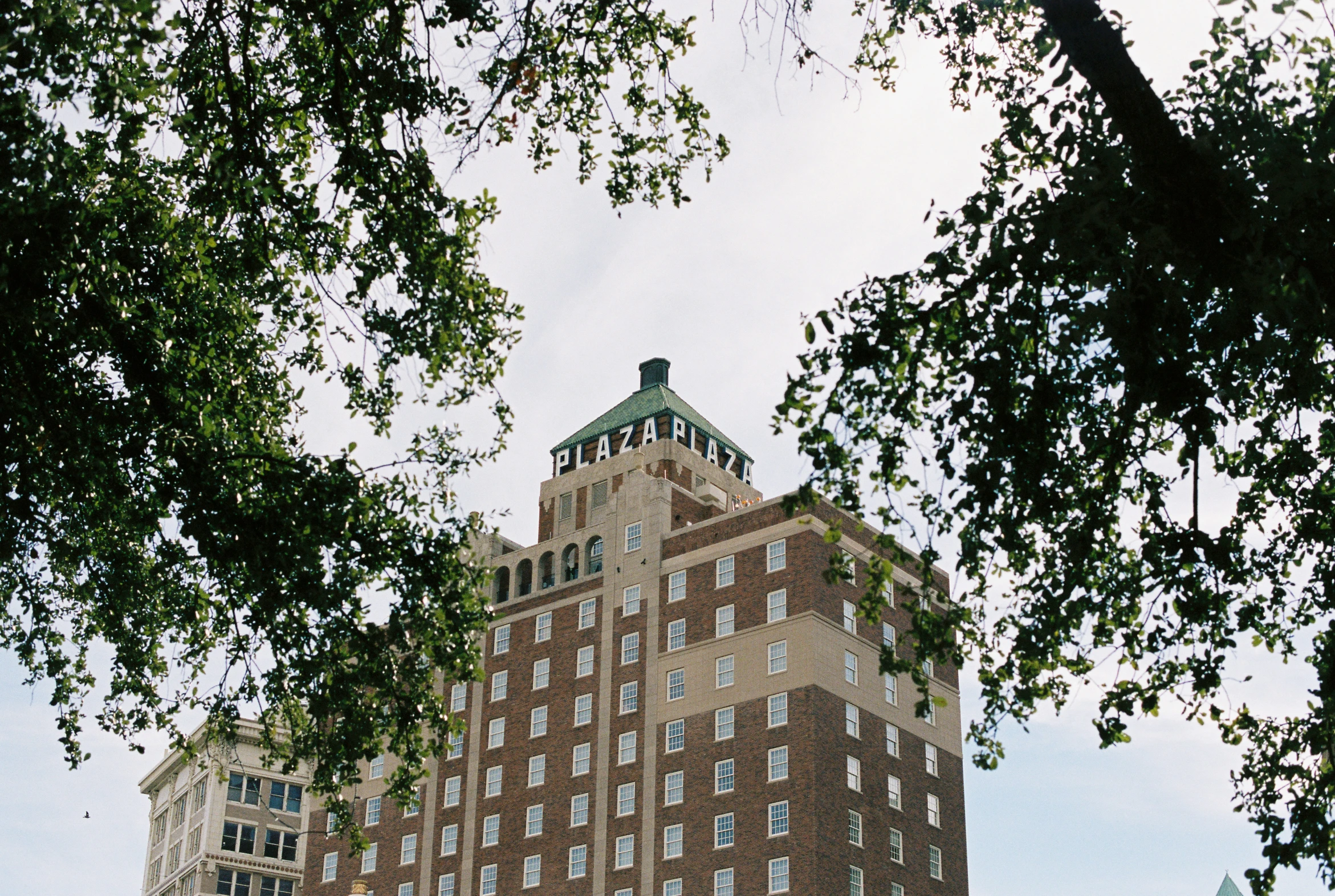 an old brick tower building under a large leafy tree