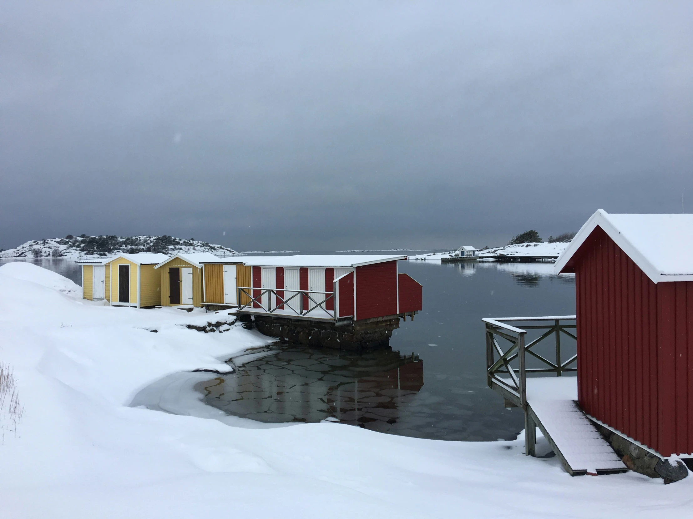 red buildings are set up next to the water on a snowy day