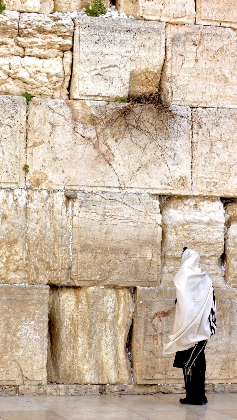 a person walking on the street in front of a wall