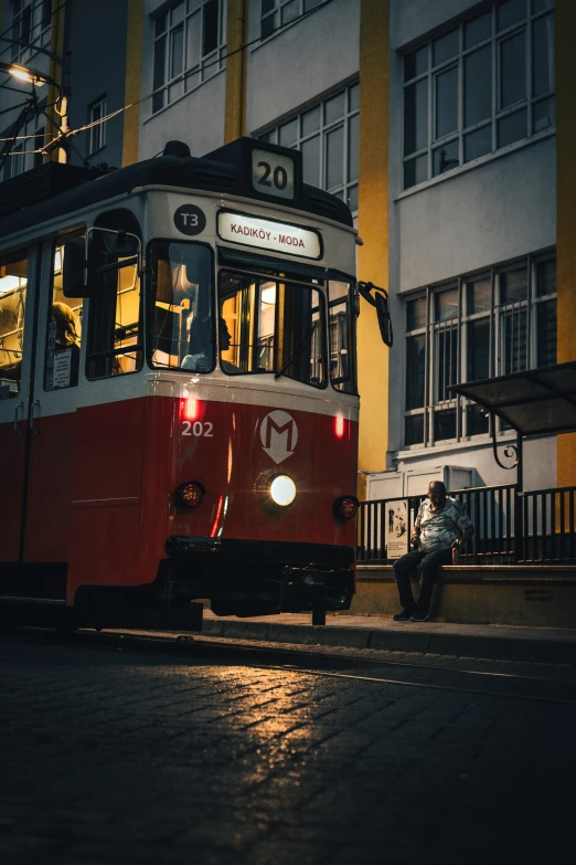 a red and white tram is coming up the street