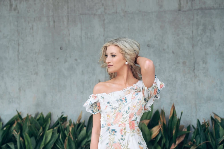 a young woman wearing a dress and posing in front of a plant