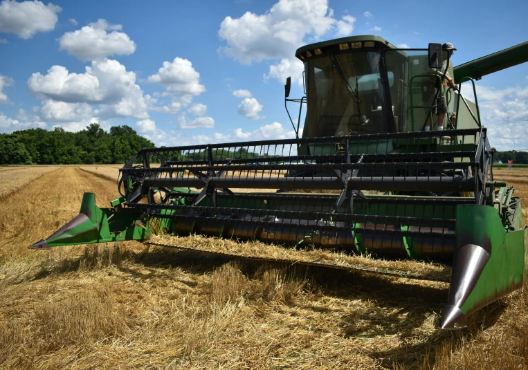 a big green field has a farm tractor in it