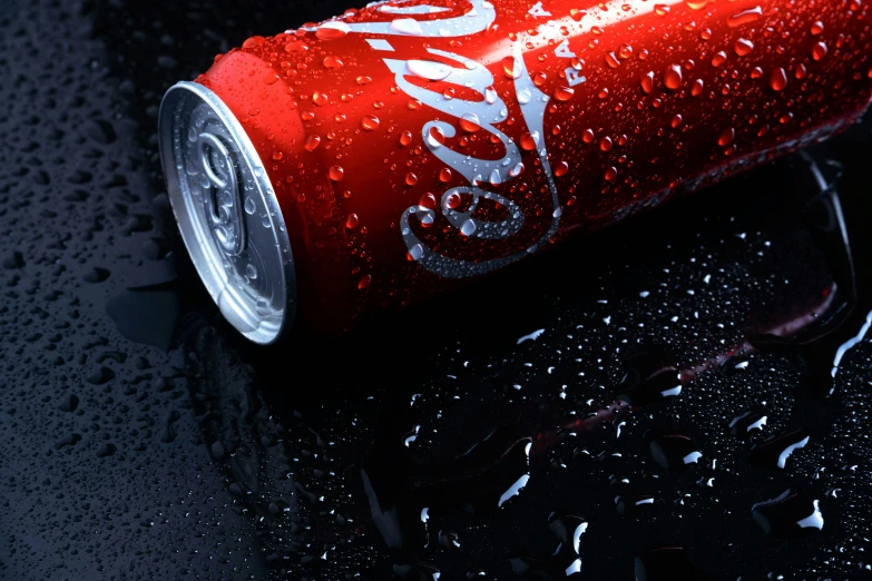 coca cola can on wet black surface with drops