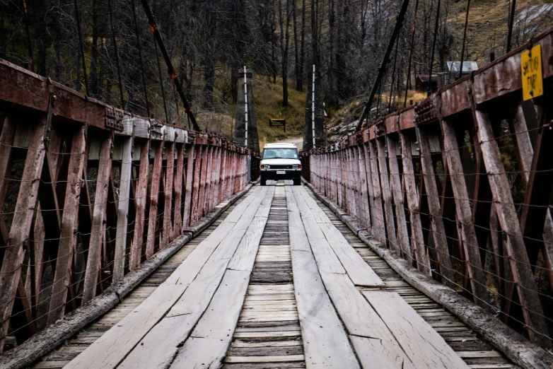 a car is driving down a wooden bridge