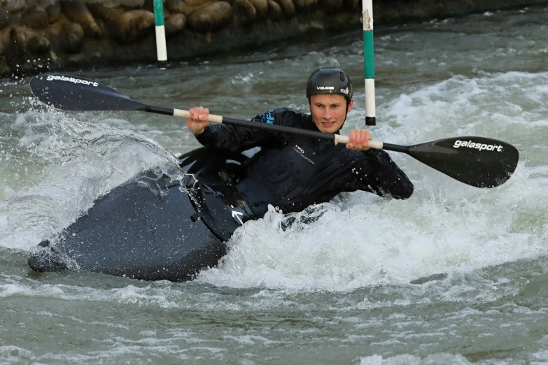 a man on a kayak on a wave in a body of water