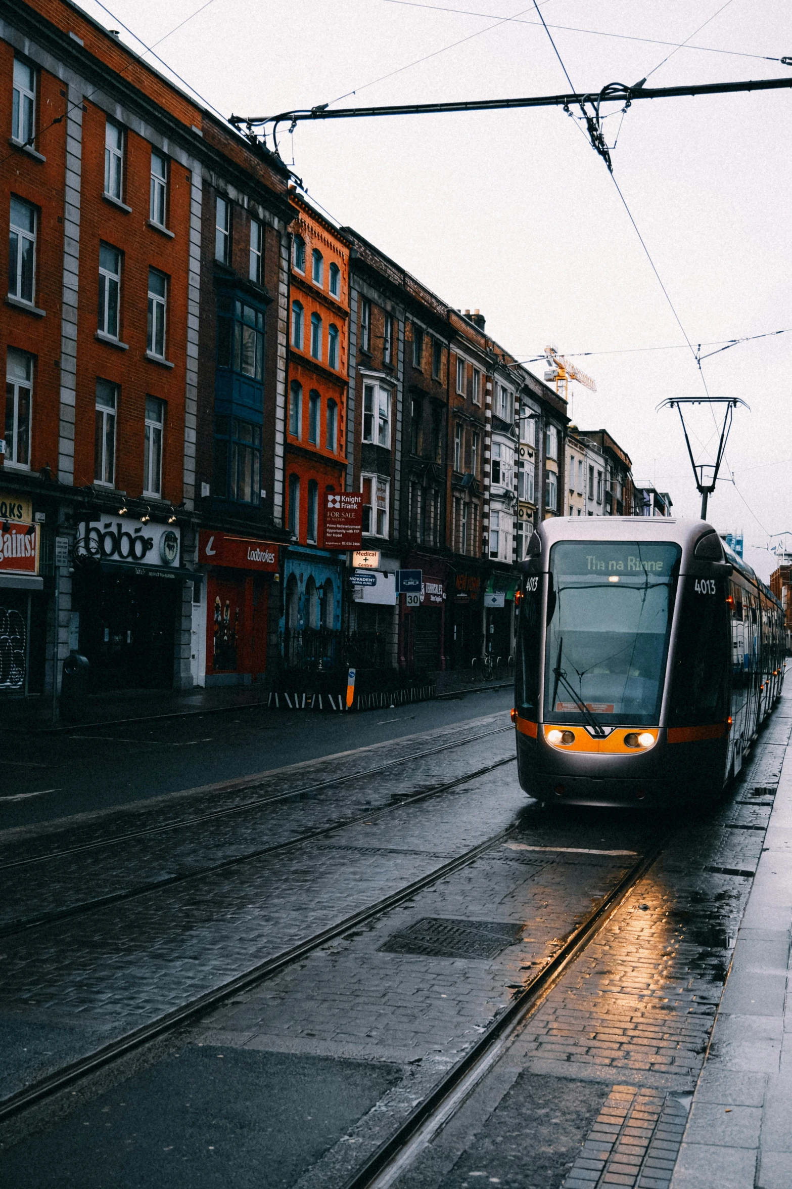 a train traveling down a street next to tall buildings