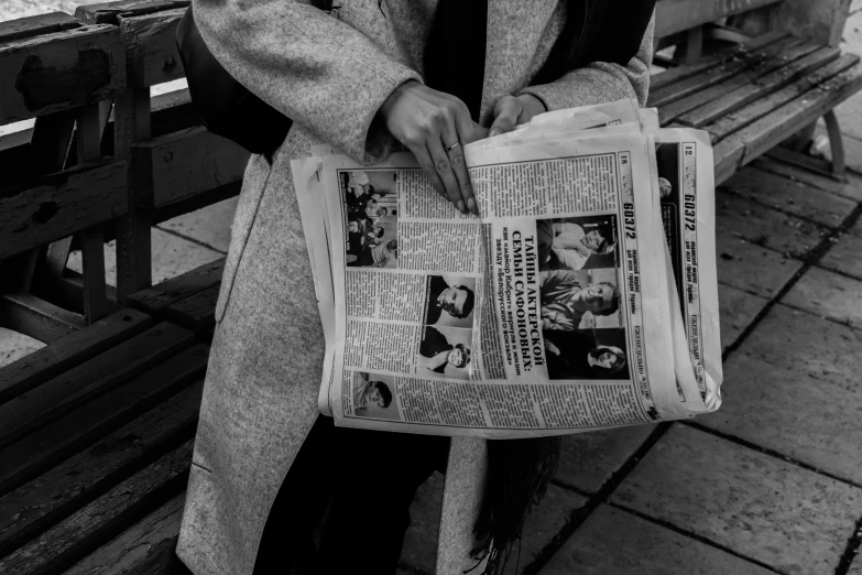 a person sitting on a park bench holding an old newspaper