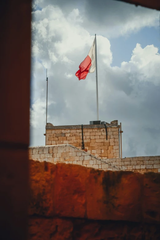 a red and white flag on top of a stone building