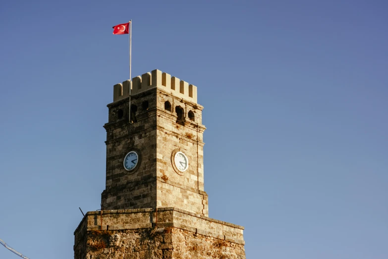 a clock tower with a flag on top and two clocks