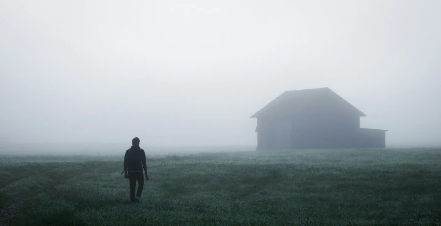 a man walking away from the camera in the fog