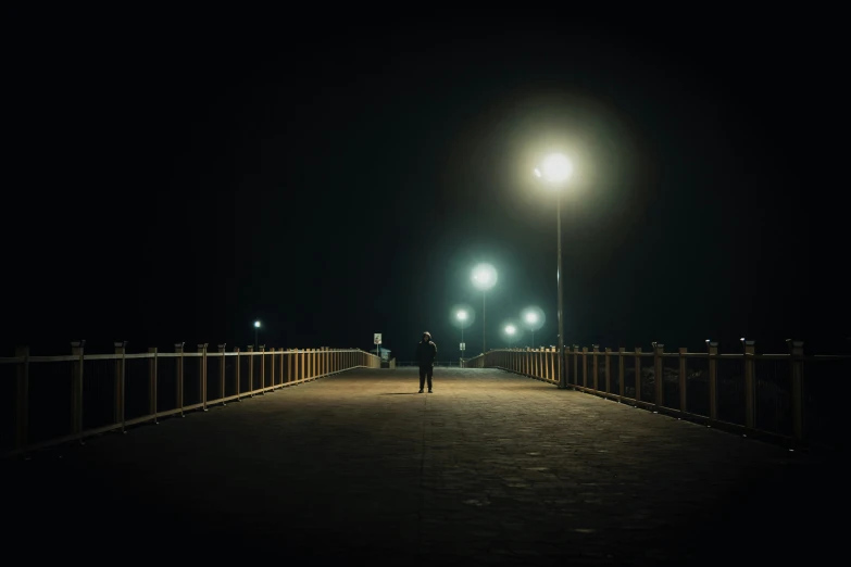 a person standing on a bridge next to a street lamp