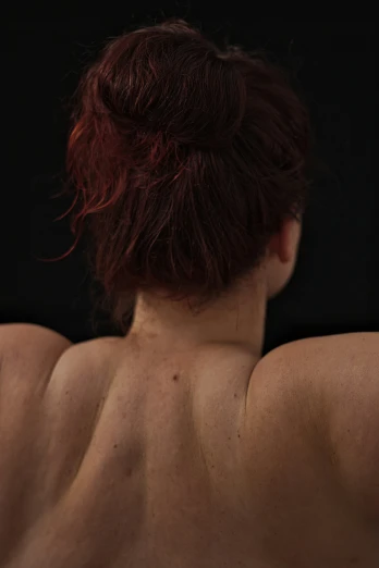 the back of a woman's topless body looking downward