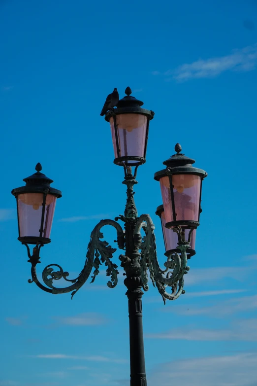 three light street lamp with blue sky and clouds in background